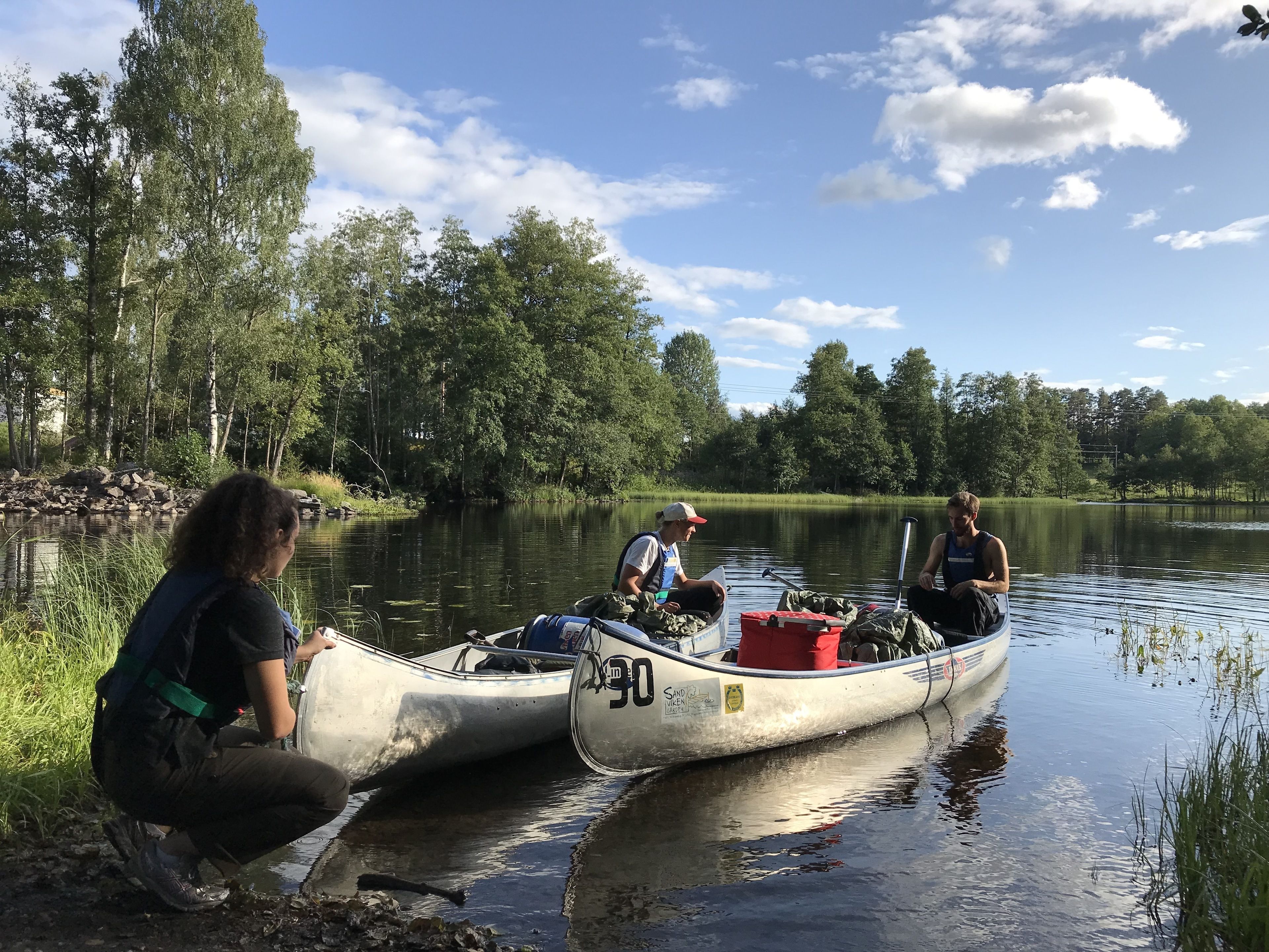 Deux canoës sur un lac paisible, entouré d’arbres.