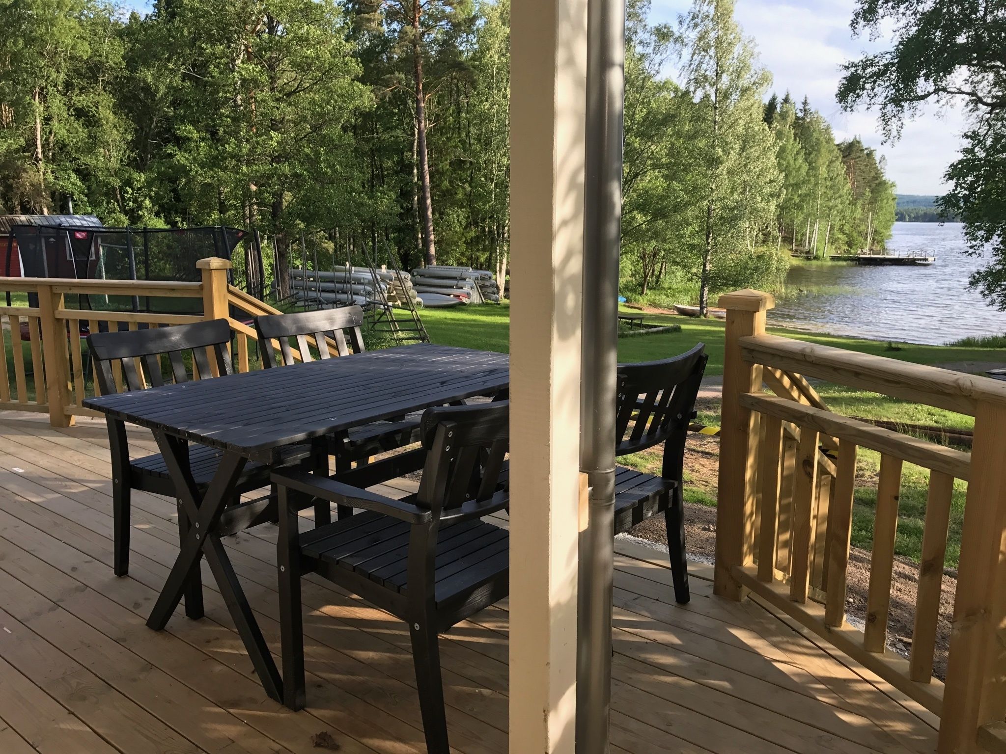 An outdoor deck with a table and chairs, overlooking a lake with boats and a dock.