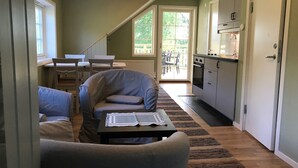 Un espai habitable reduït amb sofà, taula petita, zona de cuina i taula de dinar amb cadires.