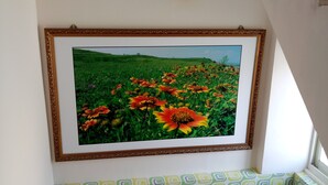 A framed landscape painting on a wall, a patterned bench, and a ceiling light fixture. - Yu Lei B&B (Huxi)