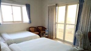 A hotel room with two beds, a table with chairs, a fan, and a view through the window. - Yu Lei B&B (Huxi)