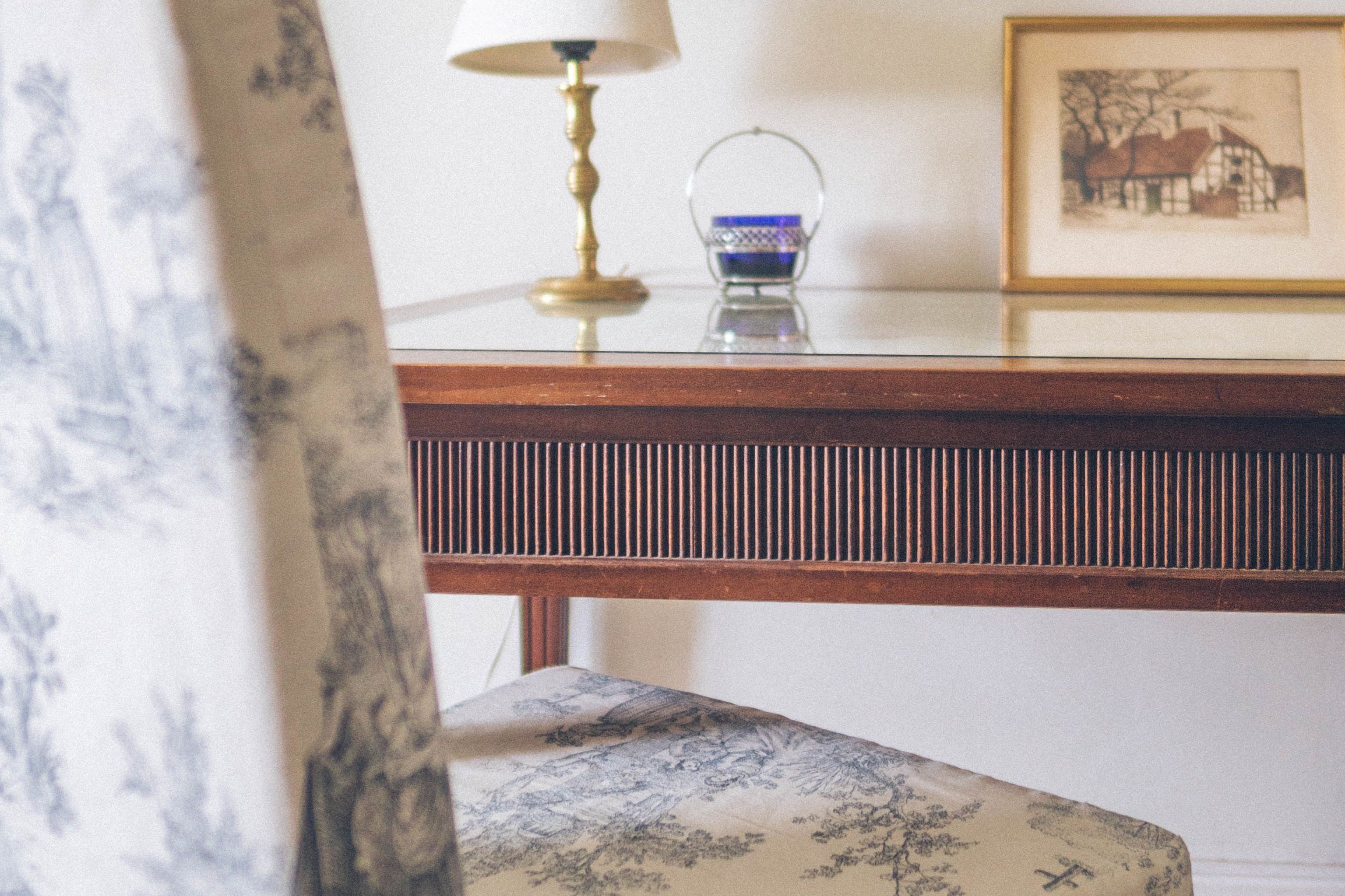 A wooden table with a lamp and a framed picture.