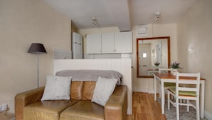 A compact living space with a sofa, a dining table, and a kitchenette in the background.