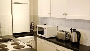 A kitchen with white cabinets, a microwave, a toaster, and a kettle.