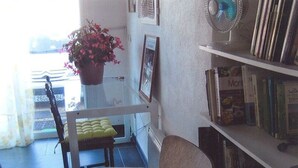 A room with a glass table, a chair, a potted plant, a bookshelf, and a window. - B&B Chez Rose-Marie (Vaison-la-Romaine)