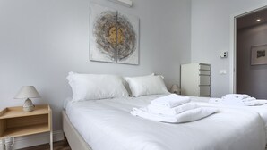 A hotel room with a neatly made bed, a bedside table with a lamp, a wardrobe, and a large abstract painting on the wall. - Italianway Corso Lodi 121 (Milan)