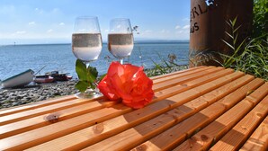 Una mesa de madera con dos copas de vino blanco y una rosa roja.