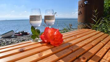 A wooden table with two glasses of white wine and a red rose.