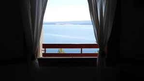Une pièce offrant une vue sur une vaste étendue d’eau, visible à travers de fines rideaux.