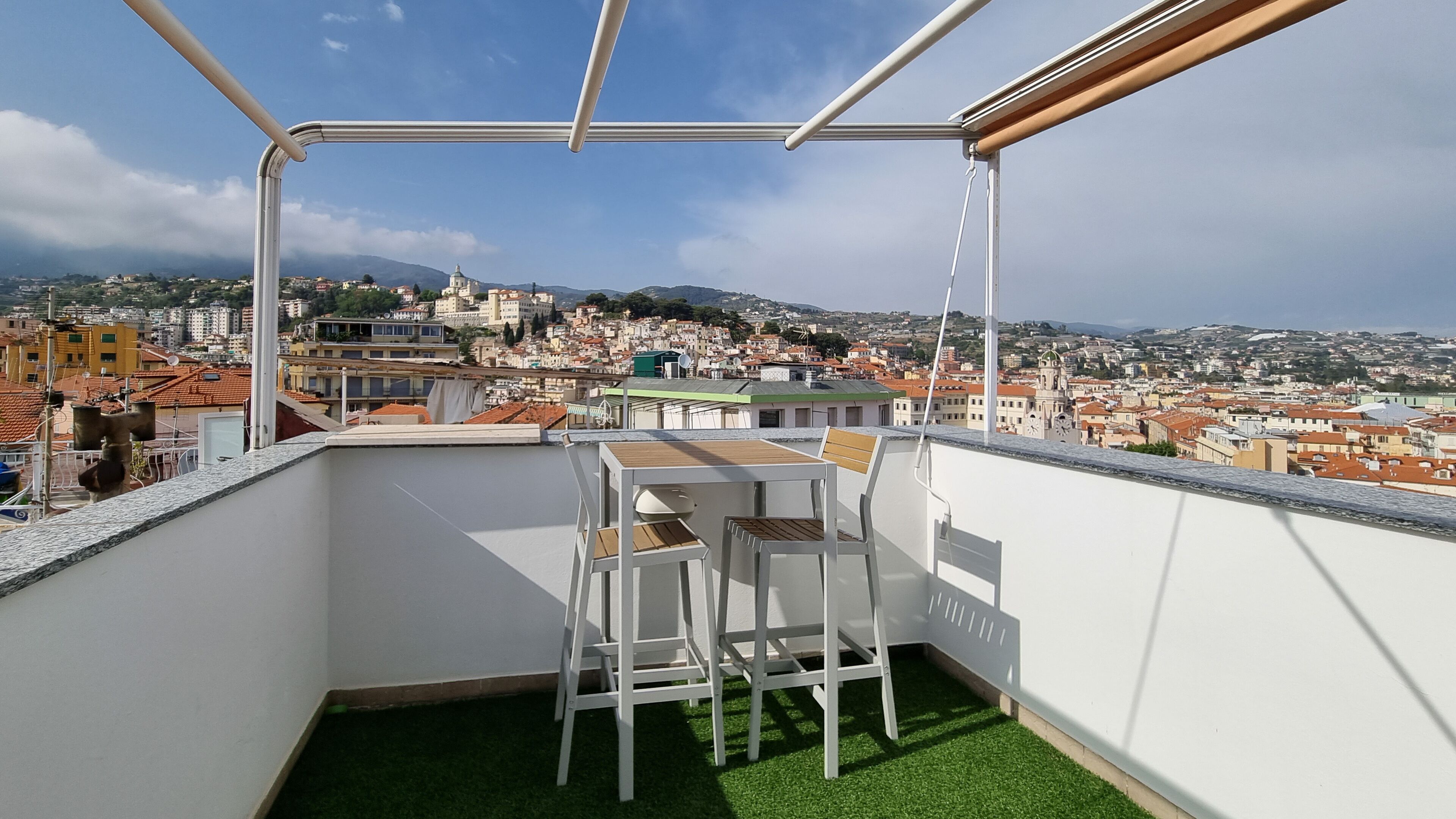 Un balcón con mesa y sillas, con vistas a un paisaje urbano con edificios y una iglesia.