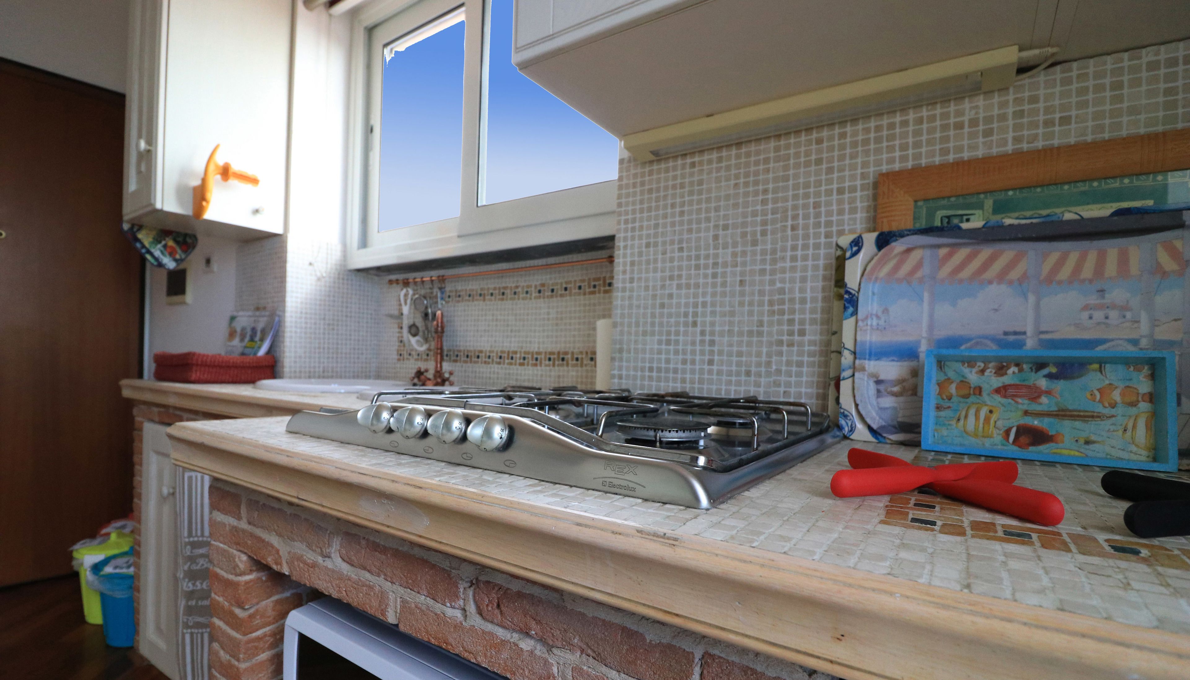 A kitchen with a gas stove, a tiled backsplash, and a window.