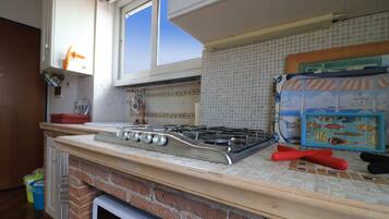 A kitchen with a gas stove, a tiled backsplash, and a window.