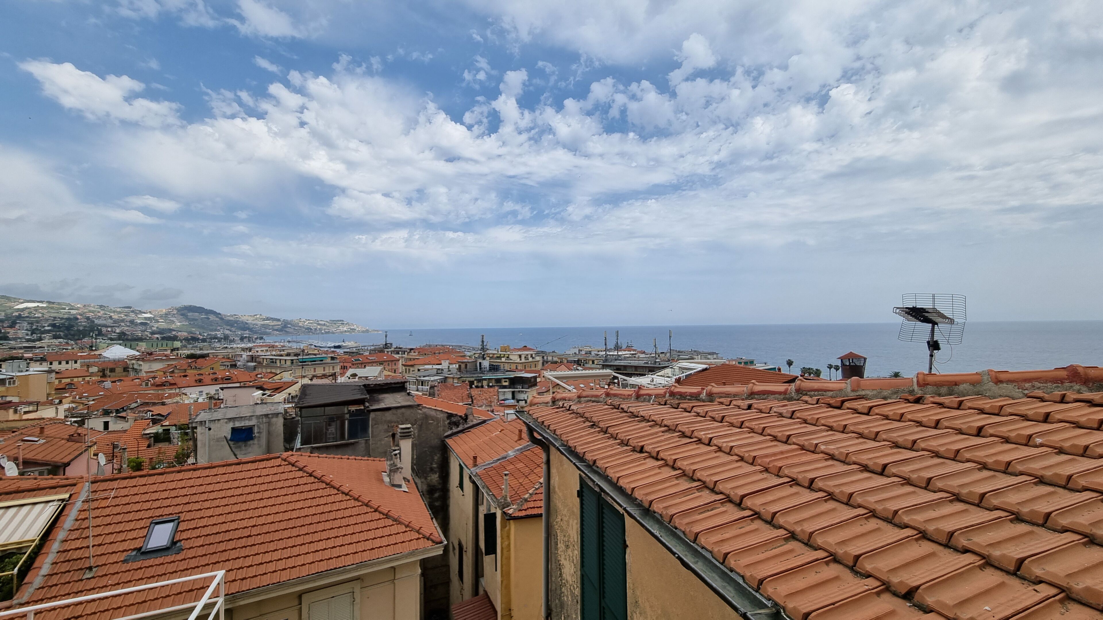 Eine Küstenstadt mit Häusern mit Terrakotta-Dächern, wolkenlosem Himmel und Blick aufs Meer.
