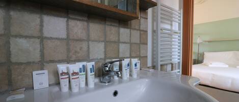 A bathroom with a white sink, a mirror, and toiletries on the counter.