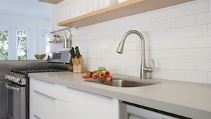 A modern kitchen with white cabinets, a Bosch dishwasher, a stainless steel sink, and a wooden countertop. - Sand Bungalow at the Lazy Hummingbird (Summerland)