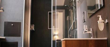 A modern bathroom with a glass shower enclosure, a wooden vanity, and a large mirror.