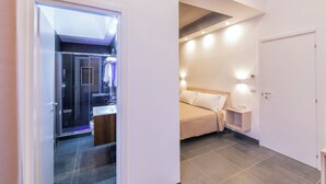 Una habitación de hotel moderna con zona de ducha, una cama y una mesita de noche.