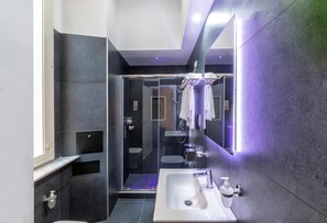 Une salle de bain moderne avec une douche à parois de verre, un lavabo blanc et un grand miroir.