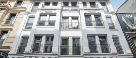 A multi-story building with a classic architectural style, featuring large windows and decorative railings. The building has a prominent sign for "HHK Hotel Downtown" on its facade.