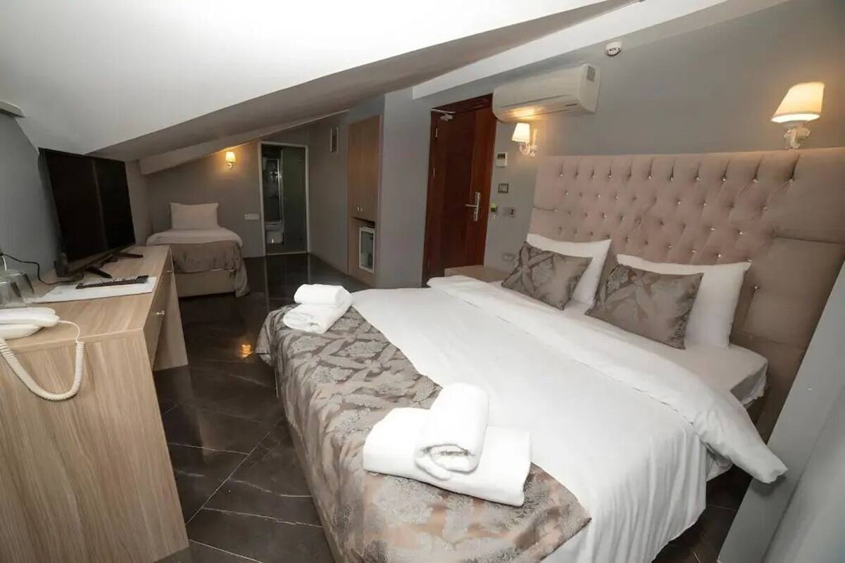 A hotel room with a bed, a desk, a chair, a TV, and a bathroom.