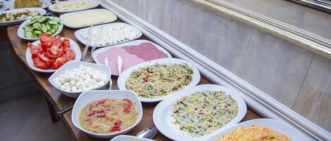 A buffet table with various dishes including pasta, salads, and a large omelette.