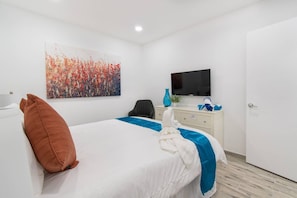 Una habitación de hotel con cama, televisor, escritorio y puerta.