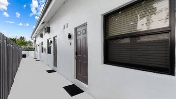 A modern building with a white exterior, a covered garage, and a clear sky.