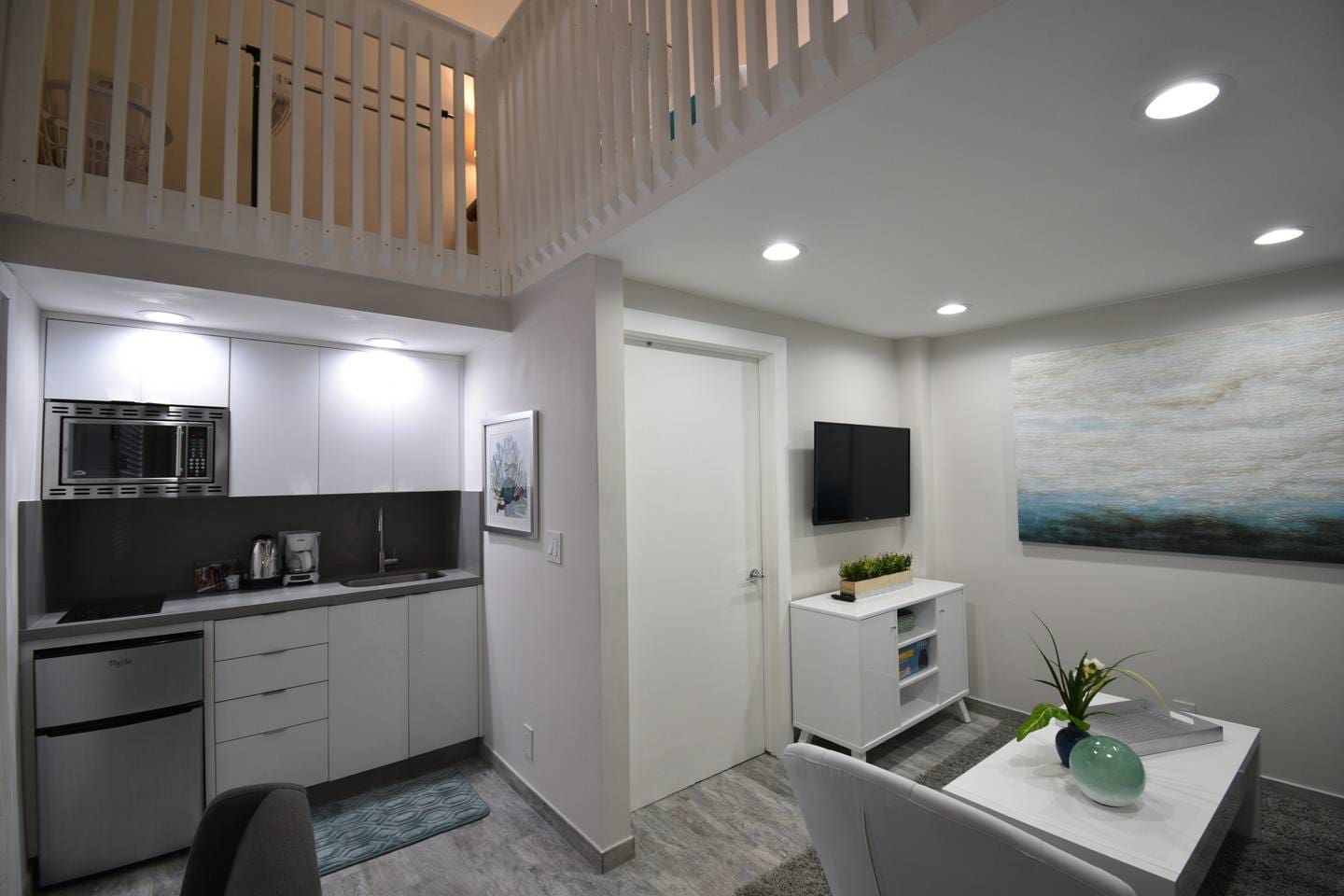 Een moderne keuken met een magnetron, koffiezetapparaat en een eethoek met een tafel en stoelen.