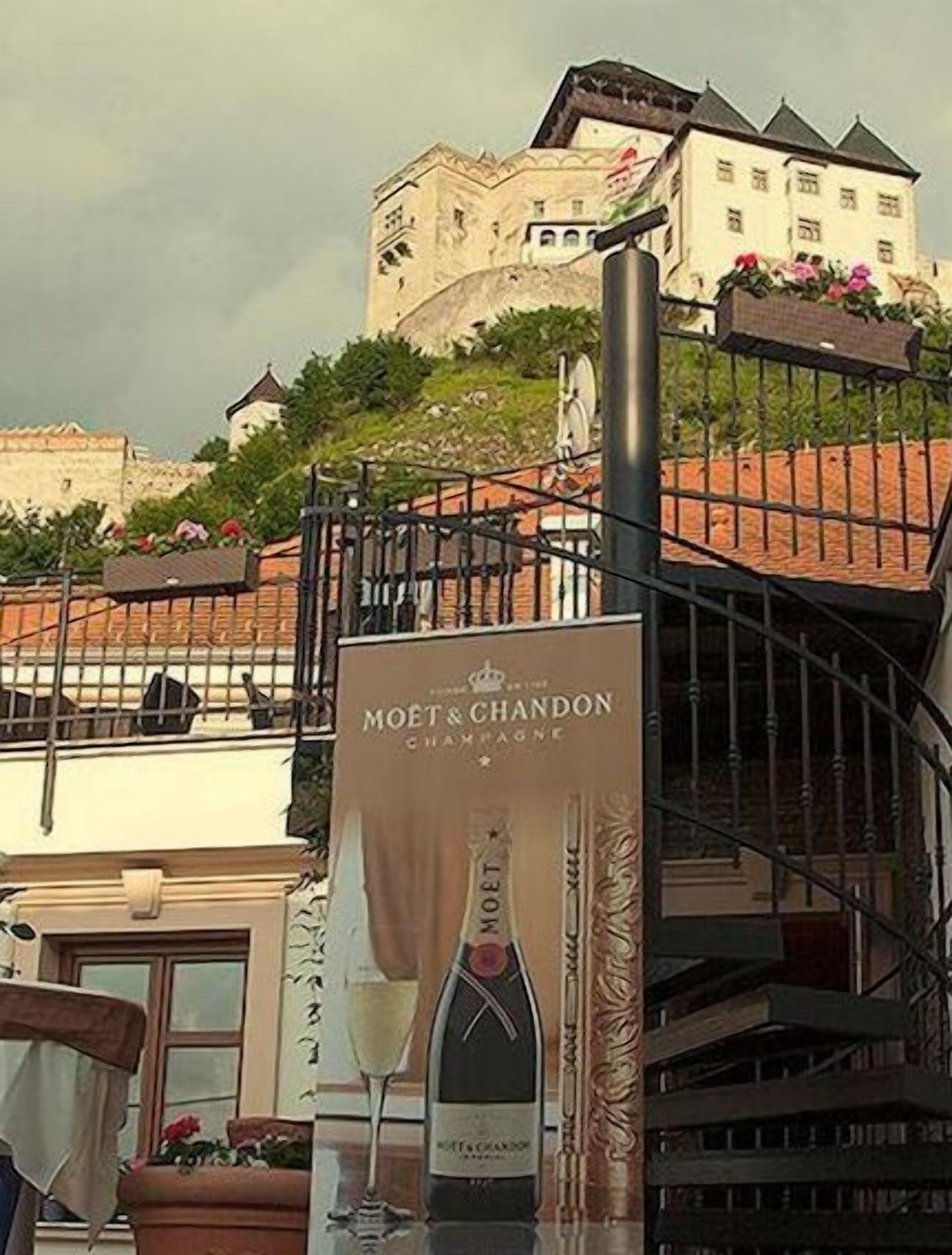 A building with a sign for Moët & Chandon champagne, a balcony, and a view of a castle-like structure in the background.