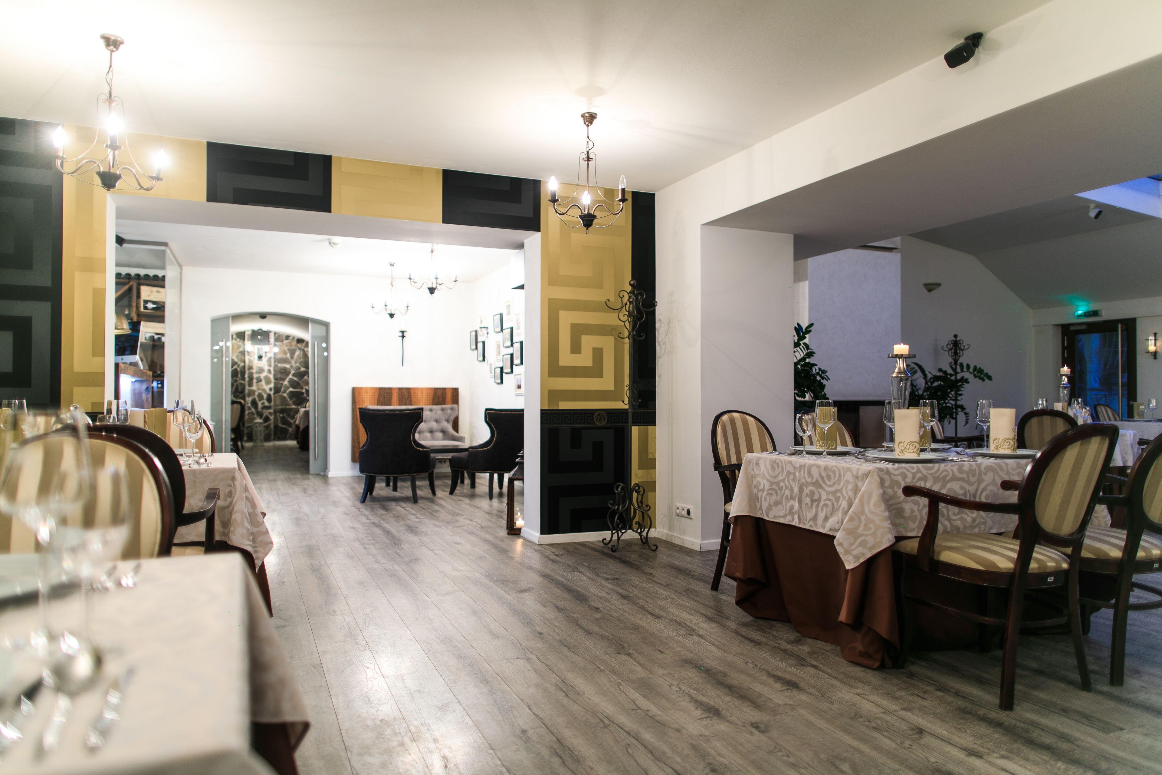 Un comedor con suelo de madera, mesas dispuestas con manteles blancos y sillas.