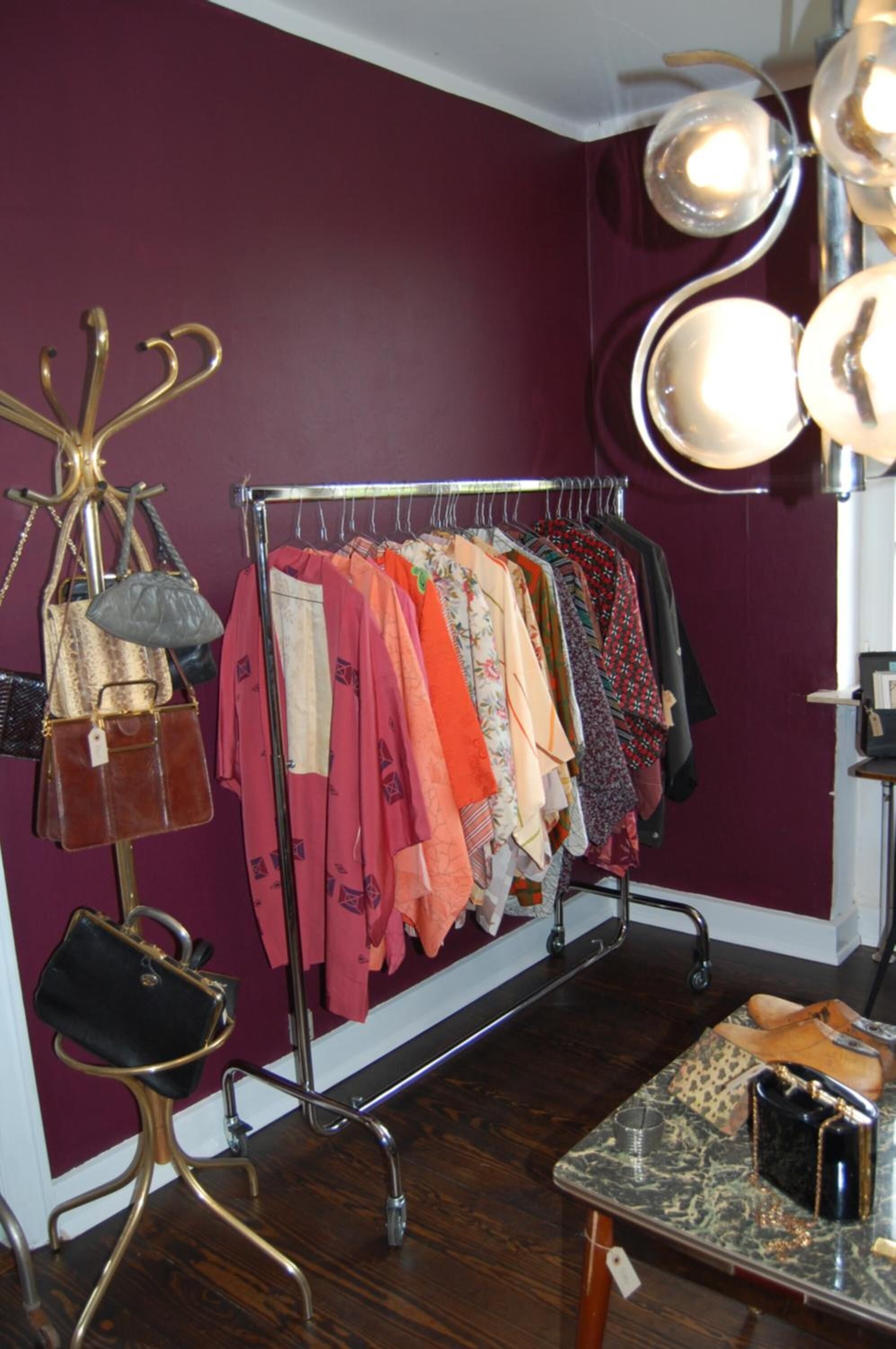 Un perchero con diferentes prendas de vestir y una exposición de bolsos.