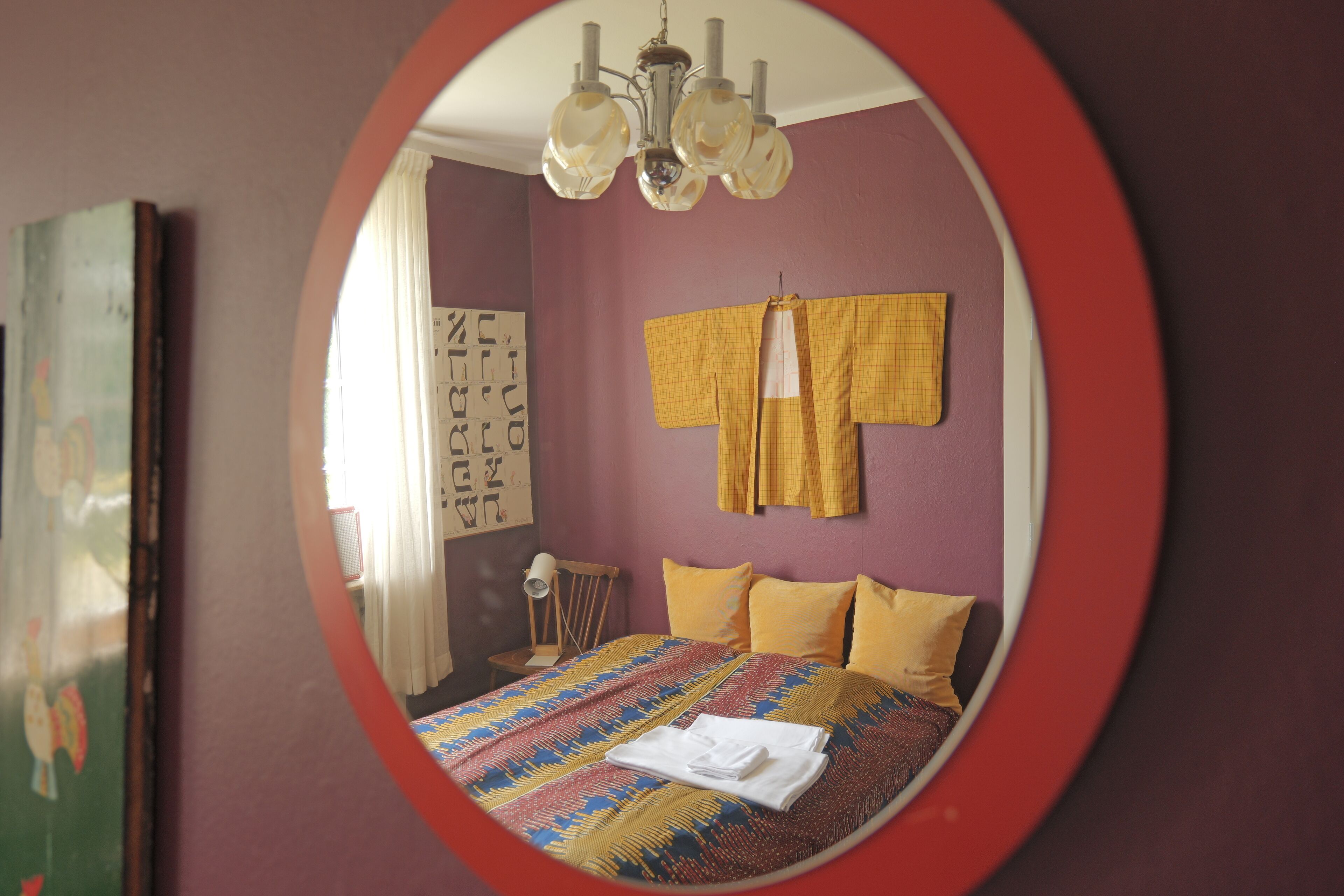 Un dormitorio con cama, espejo y ventana.