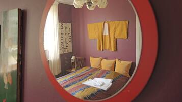 Ein Schlafzimmer mit einem Bett, einem Spiegel und einem Fenster.