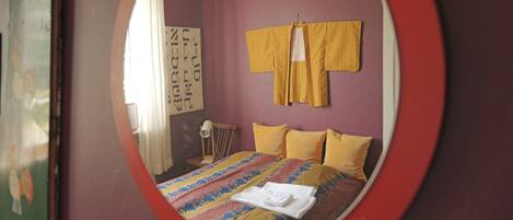 A bedroom with a bed, a mirror, and a window.