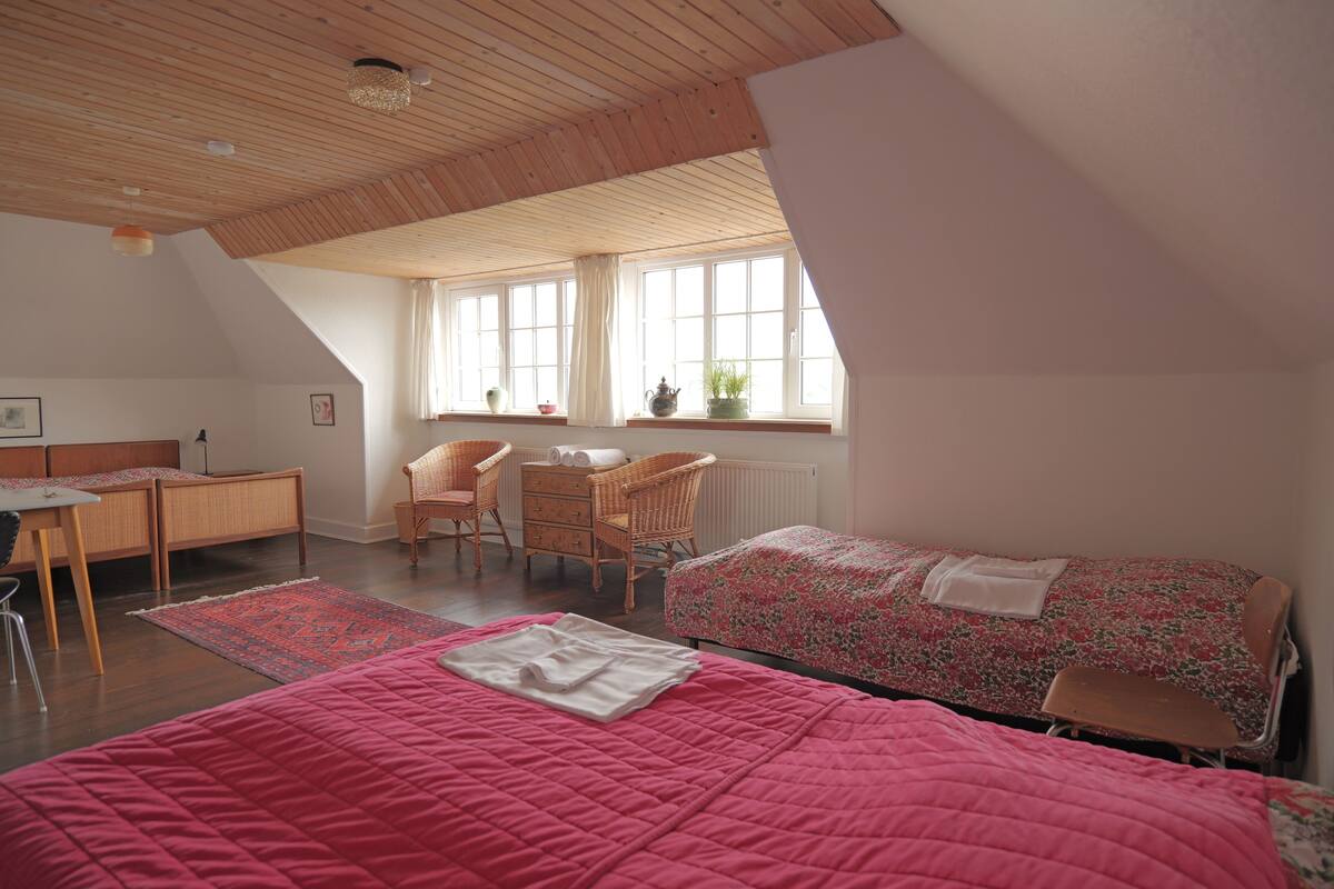Un dormitorio con dos camas, un escritorio, una silla y una ventana con cortinas.