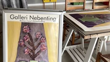 Una obra de arte enmarcada titulada 'Galeri Nebenting' de Betina Lund Hammarberg, que muestra un jarrón con flores.