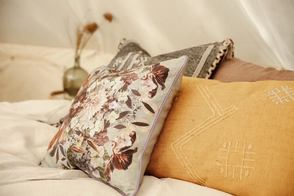 A bed with floral and geometric patterned pillows.