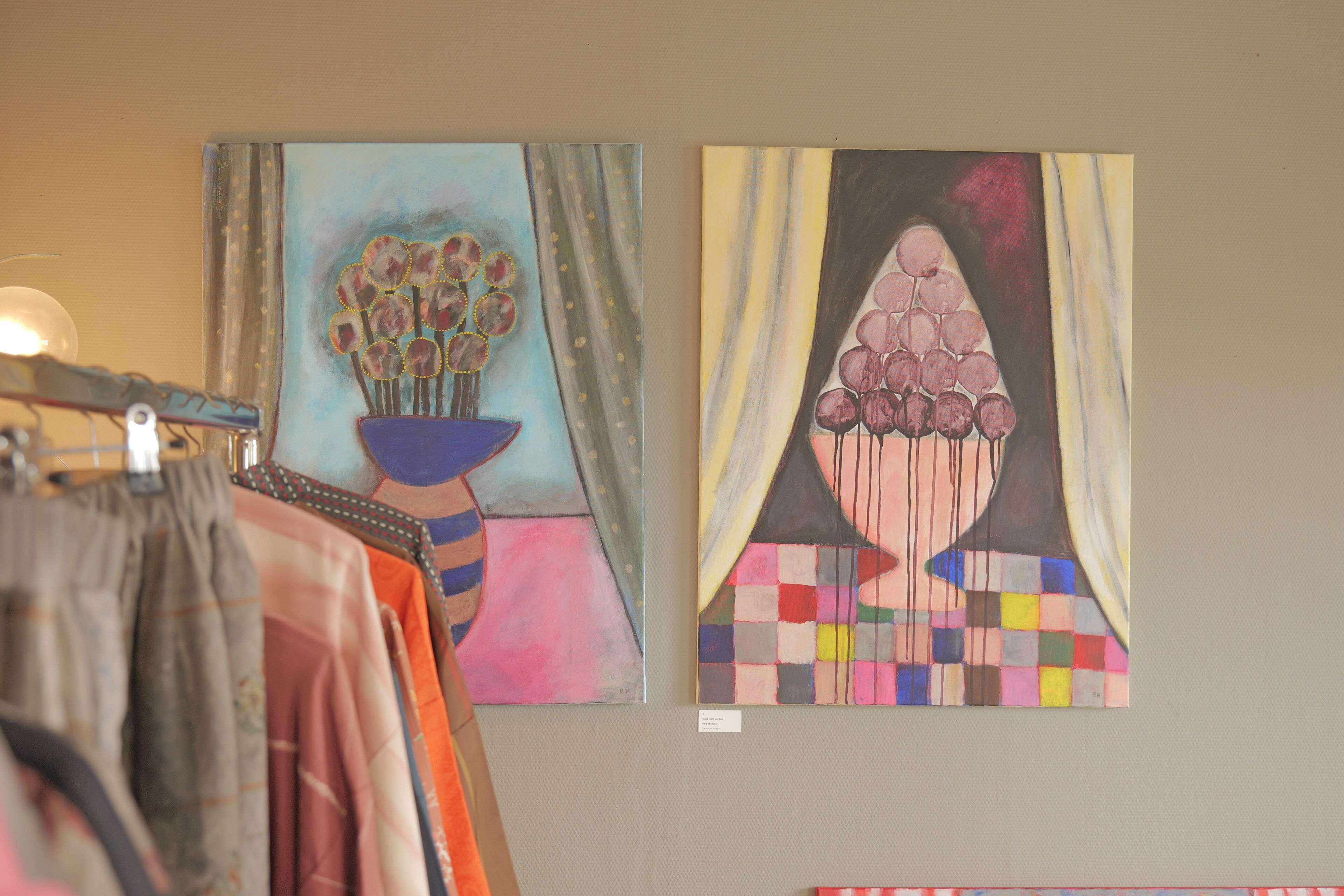 Two artworks on a wall, one depicting a vase with flowers and the other a geometric pattern.