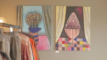 Two artworks on a wall, one depicting a vase with flowers and the other a geometric pattern.
