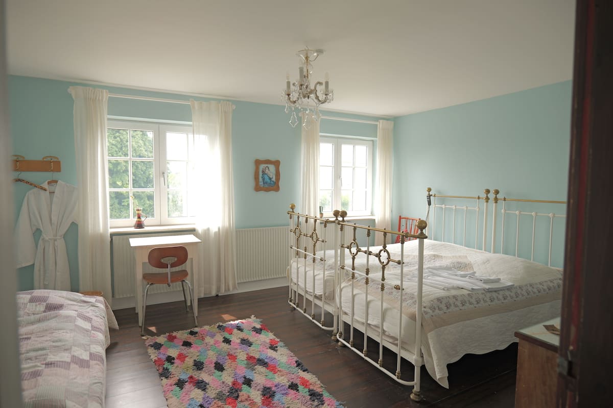 Un dormitorio con cama, escritorio, silla y candelabro.