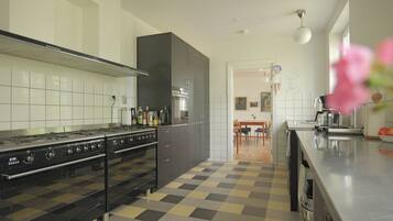 Una cocina moderna con piso a cuadros blanco y negro, electrodomésticos de acero inoxidable y vista al área de comedor.