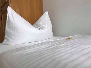 A neatly made bed with white pillows and a striped bedspread. - Gasthof zur Post (Inning A. Ammersee)