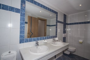 A bathroom with two sinks, a toilet, and a mirror.