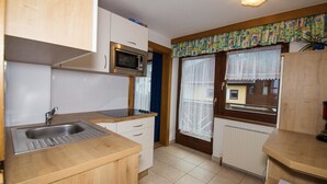 A compact kitchen with a sink, stove, microwave, and wooden cabinets.