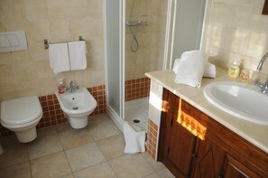 Une salle de bain comprenant des toilettes, un bidet, un lavabo et une douche.
