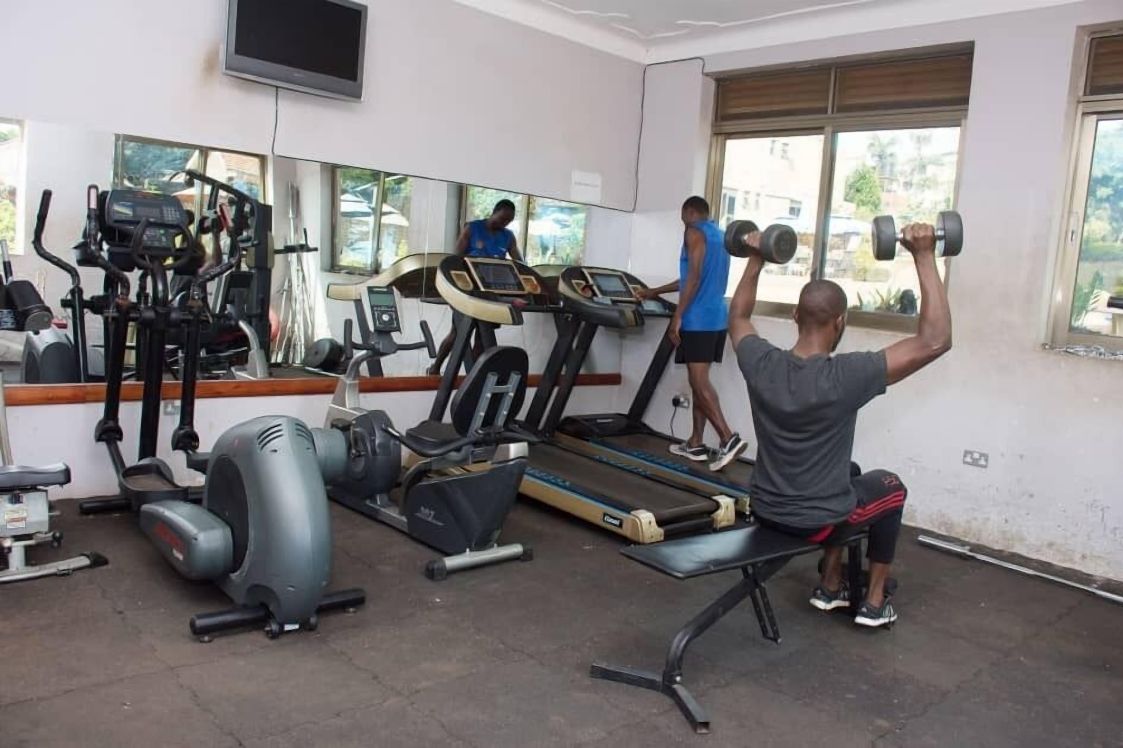 A gym with treadmills, elliptical machines, and a bench.