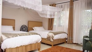 Ett hotellrum med två sängar, en fläkt, ett bord och utsikt över omgivningarna.