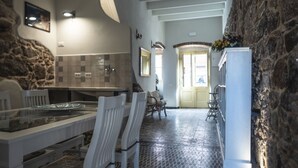 A modern kitchen with a dining area, stone walls, and a tiled floor. - Domo Sa Barra (Sant'Antioco)