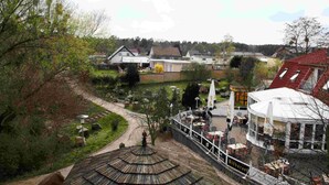 A view of a village with a restaurant named "Hotel Restaurant" featuring outdoor seating and a traditional thatched roof structure.