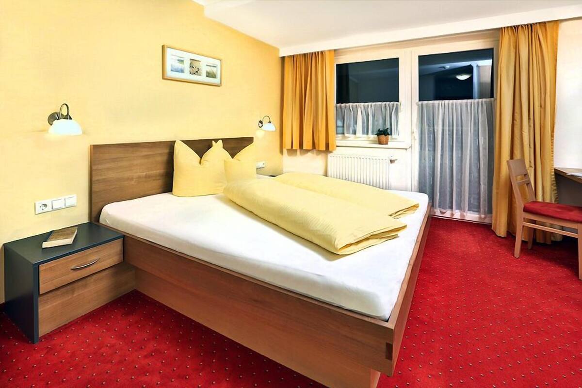 A hotel room with a bed, a nightstand, a desk, and a chair.